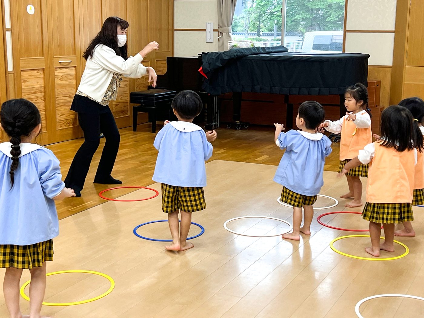遊戯室で、先生のピアノに合わせて体を動かす子どもたち