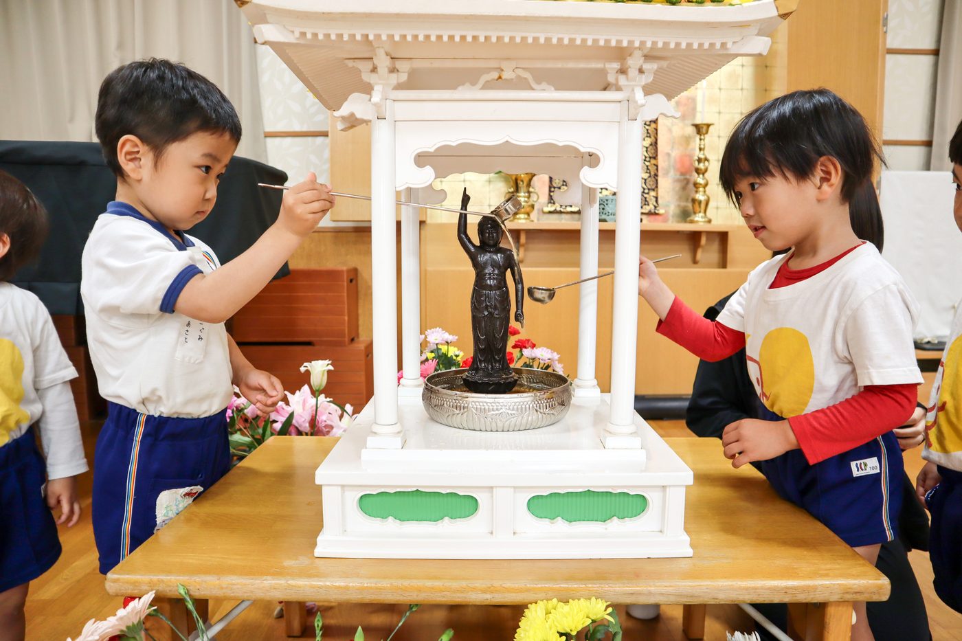 花まつりで、お釈迦さまの像に甘茶をかける子どもたち