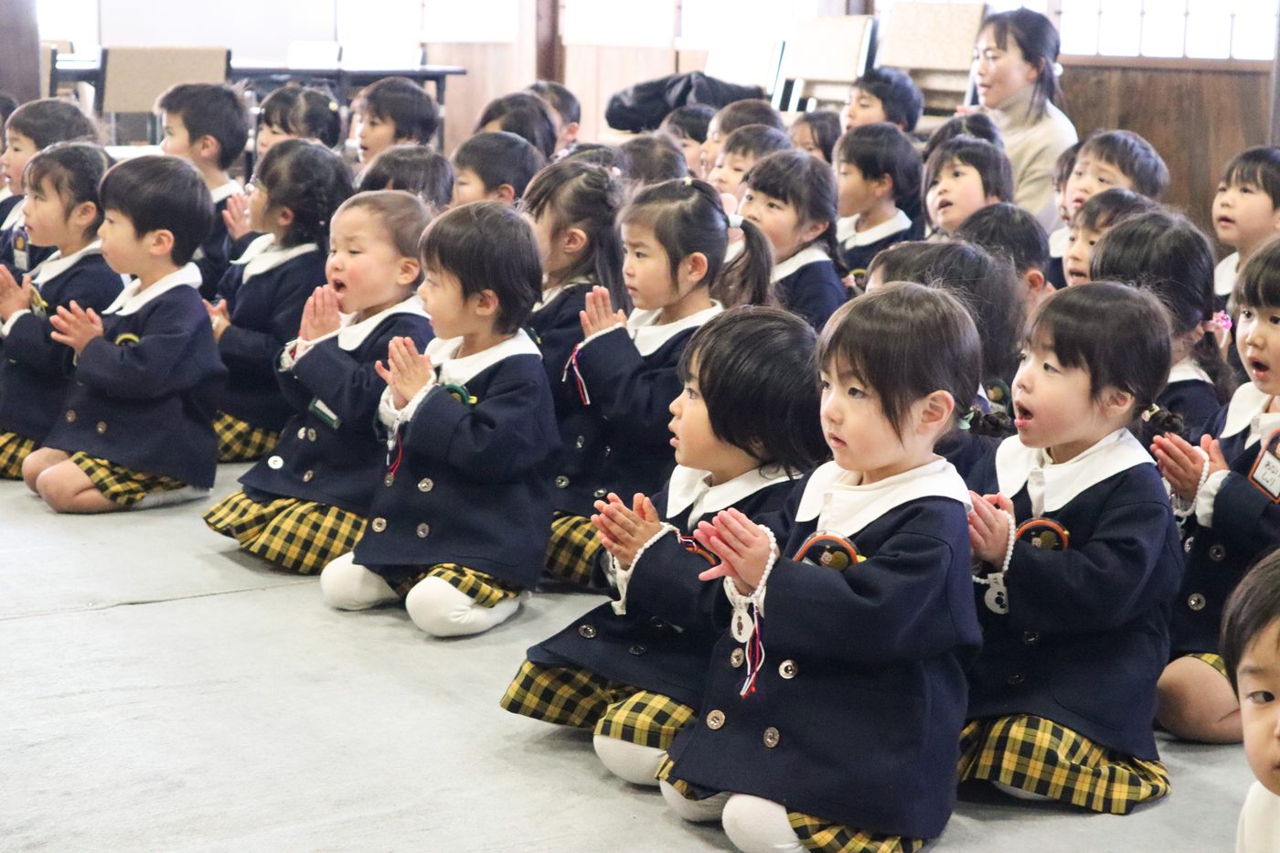 長福寺の本堂で、ご本尊に向かって手を合わせる子どもたち