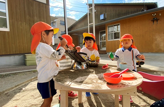 砂場でスコップやボウルを使って砂あそびをする子どもたち