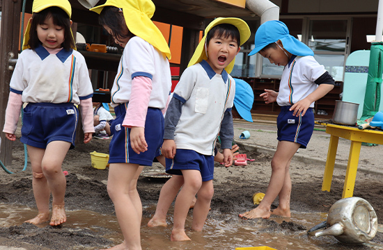 はだしになって、どろんこのエリアで水と土をこねてあそぶ子どもたち