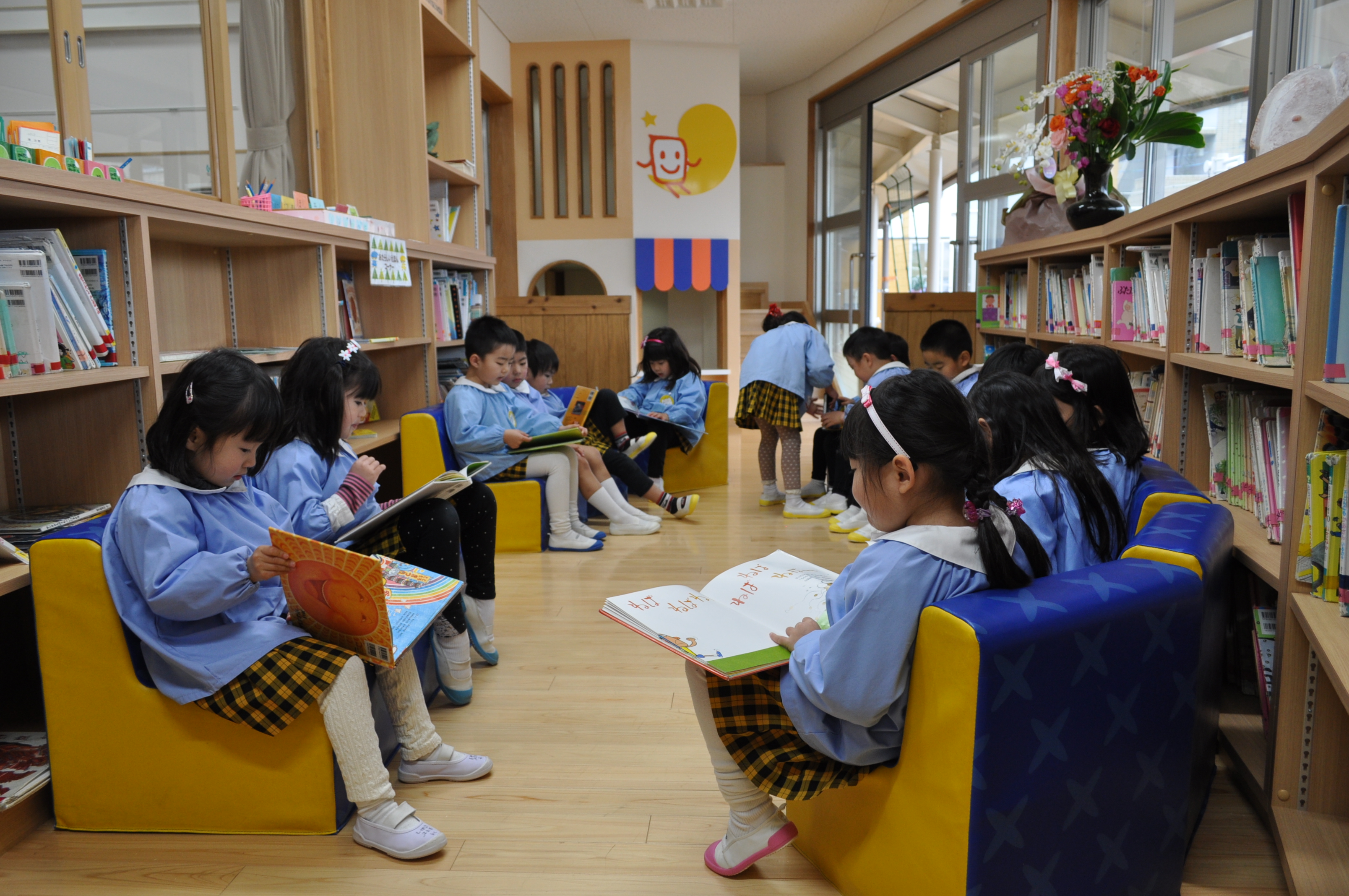 えほんの部屋のソファに座って、それぞれ絵本をひらく子どもたち