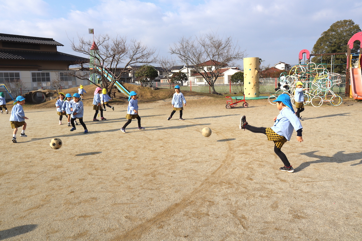 広い園庭で、ボールを追いかけて走りまわる子どもたち