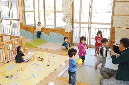 保育室のマットの上で、思い思いに遊ぶ小さな子どもたち