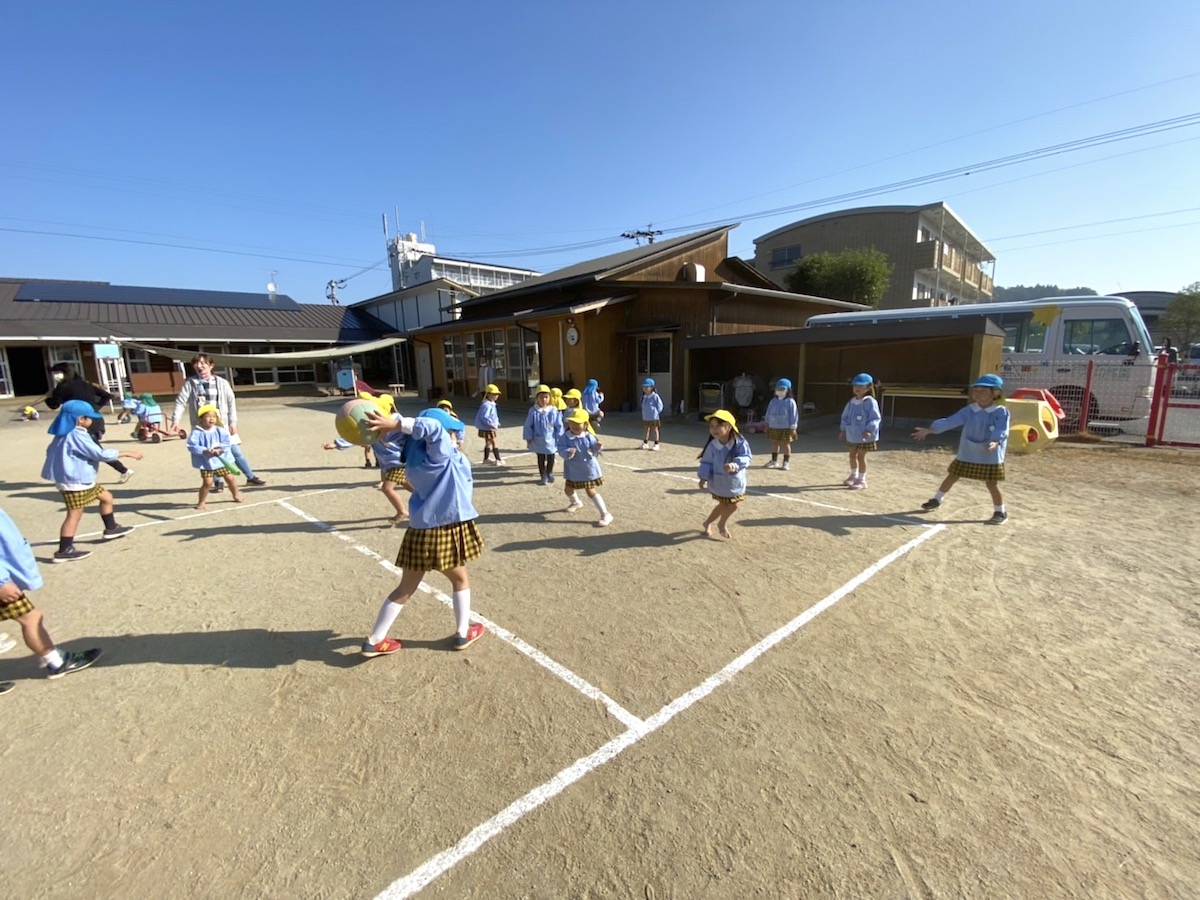 朝の園庭いっぱいに広がって、ボールを追いかけて走りまわる子どもたち
