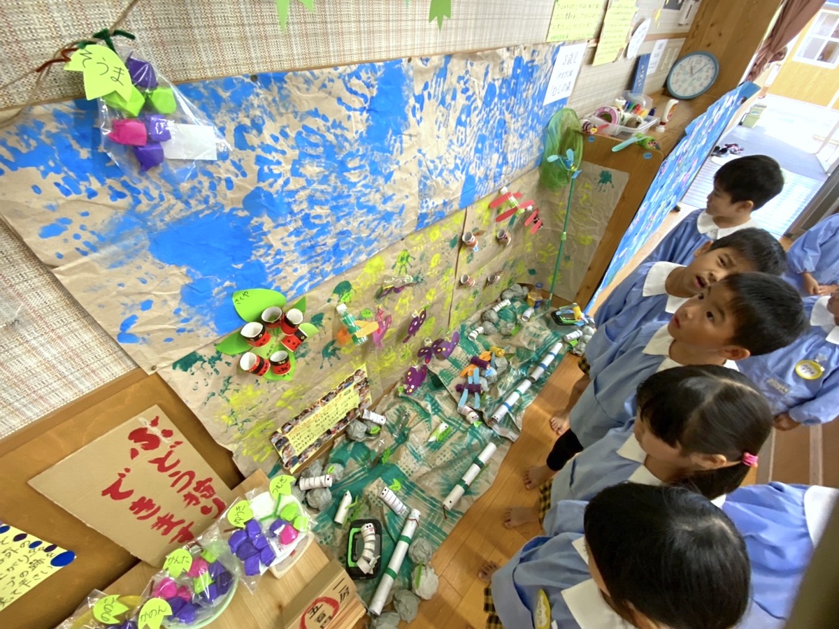 作品展で、みんなでつくった大きな作品を見上げる子どもたち
