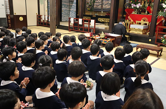 長福寺の本堂で、ご本尊に向かって手を合わせる子どもたち