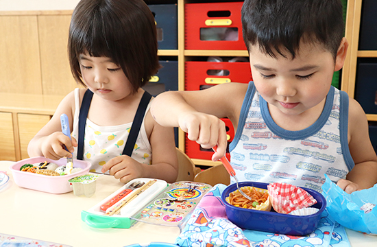 お弁当の日。ふたを開けたお弁当をのぞきこむ二人の子ども