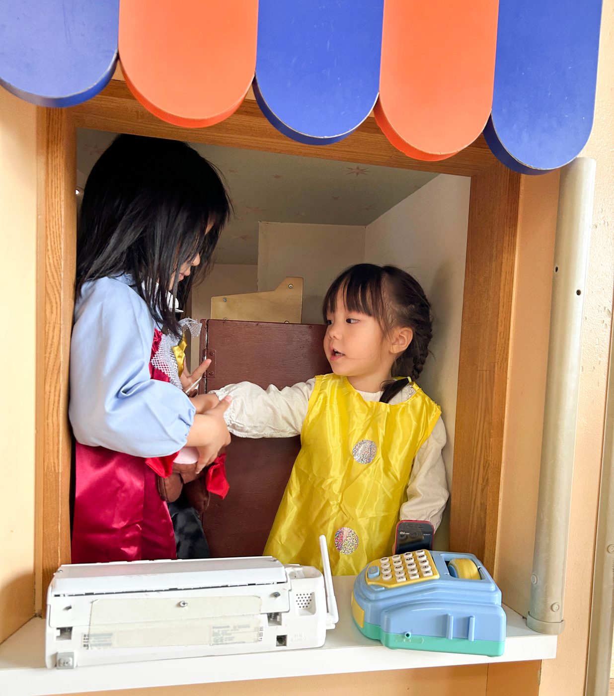 キラリハウスの窓から顔を出して、ごっこ遊びをする二人の子ども