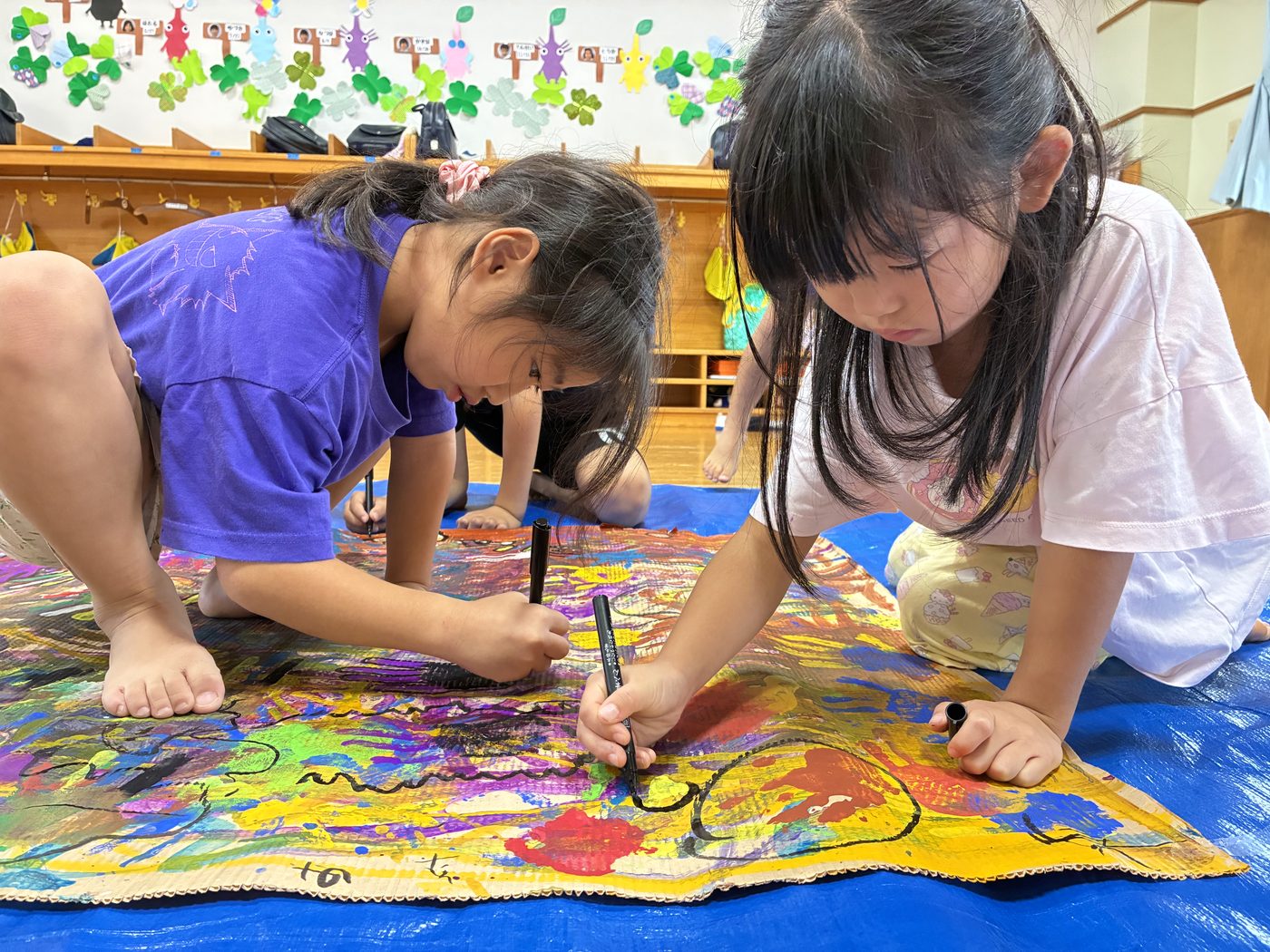 絵の具で大きな共同作品を描く二人の子ども